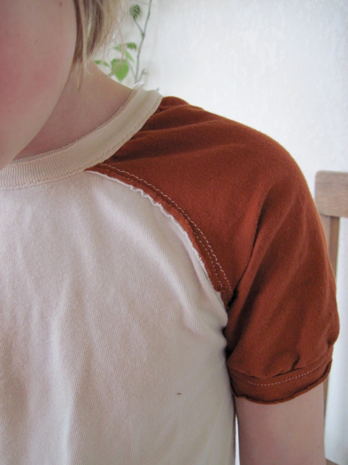 A child wearing a raglan-sleeve shirt, with the sleeve running in one piece to the collar.