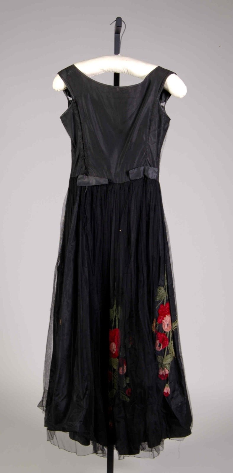 Evening dress with cutaway back panel at upper bodice edge.