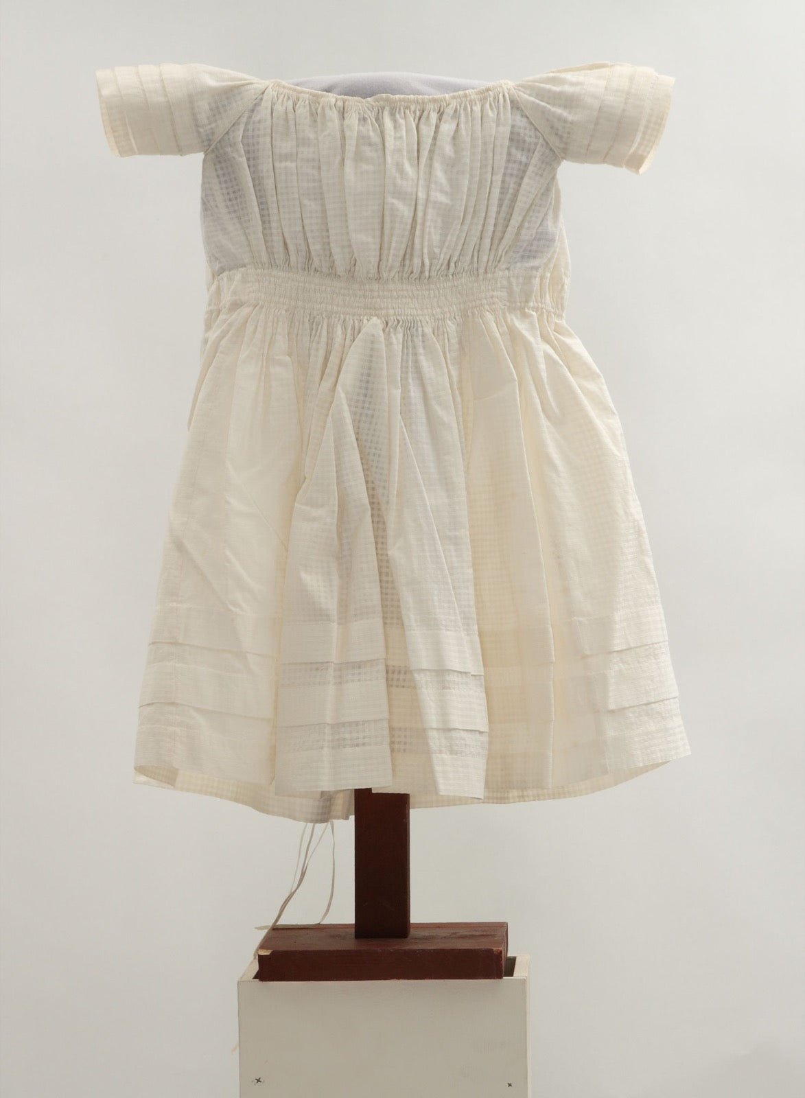 Infant dress with elastic casing gathering waist on cotton bodice.