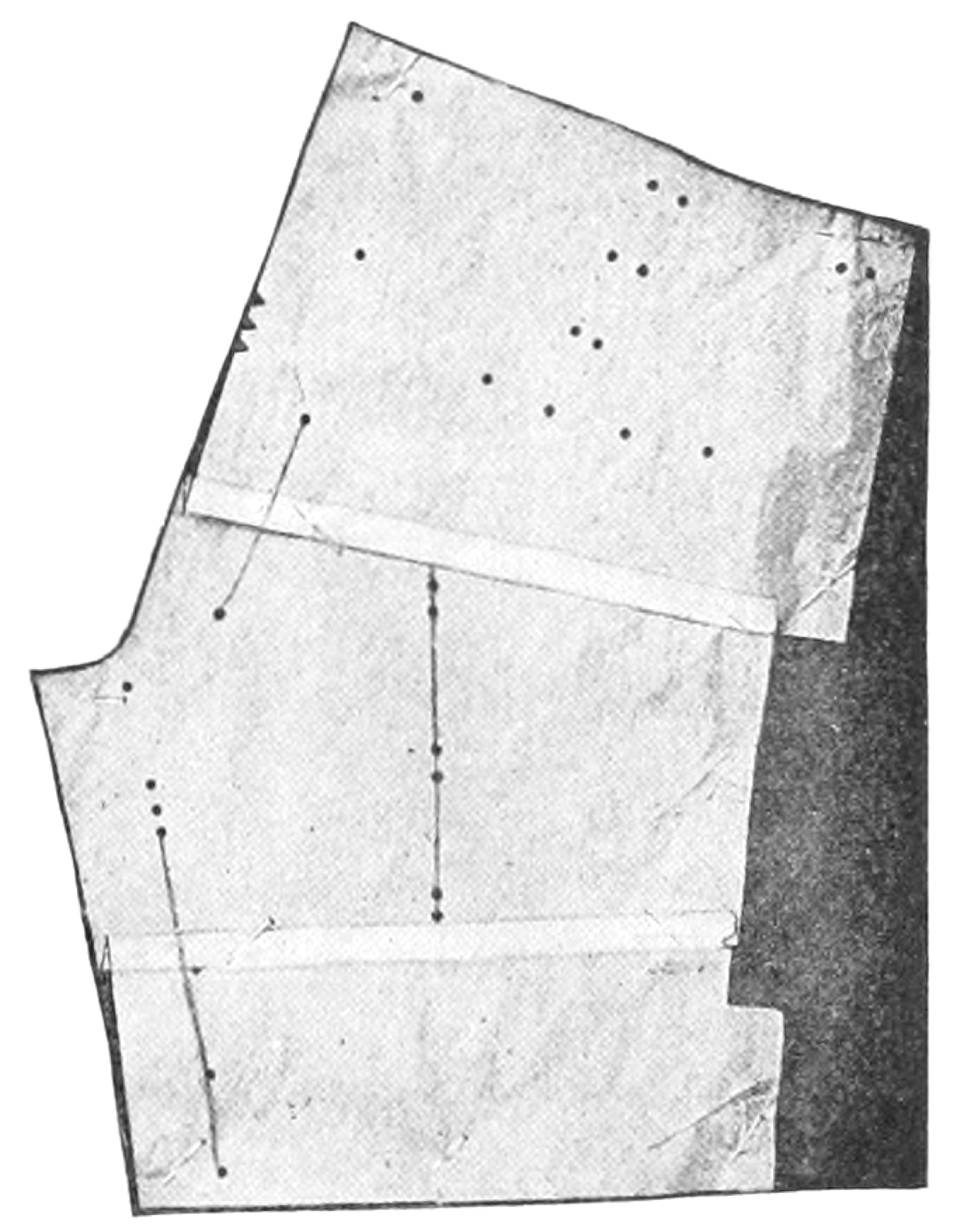 Shortening pattern of boys knickerbockers on flat pattern drafting table.