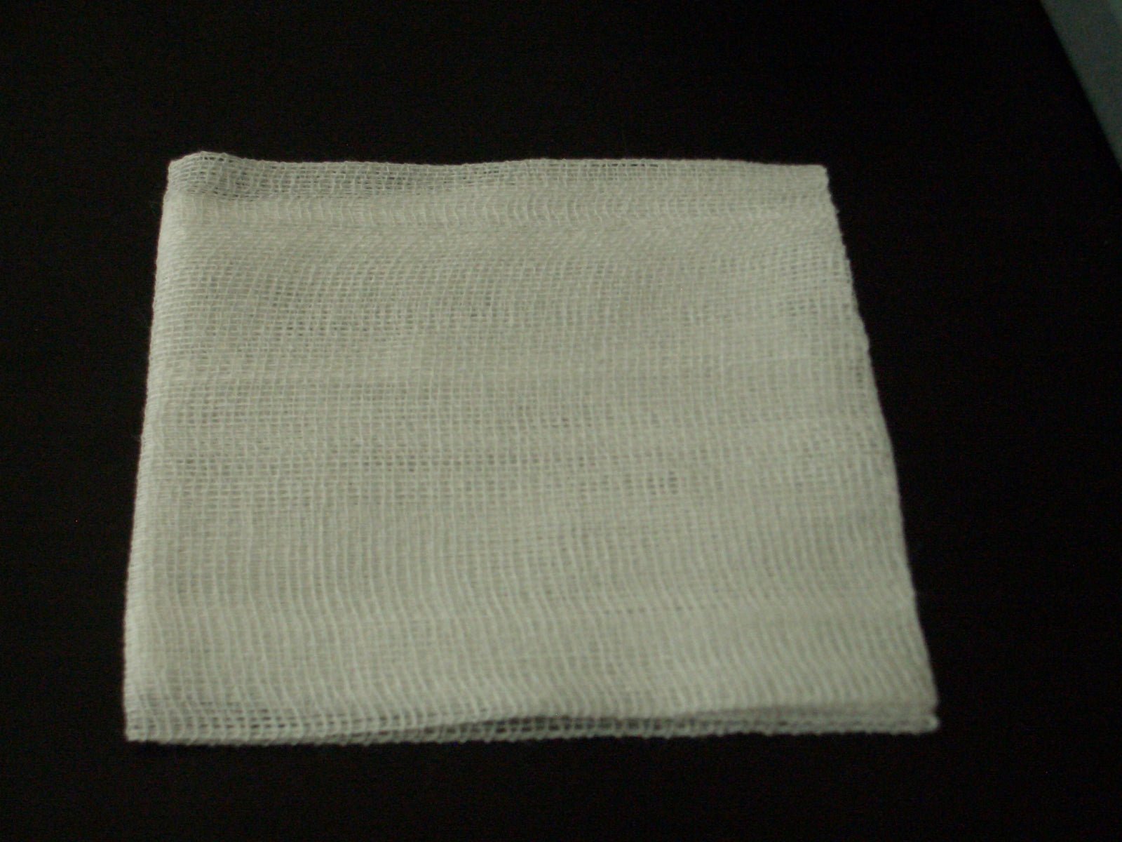 Sheer gauze fabric held up showing open mesh holes.
