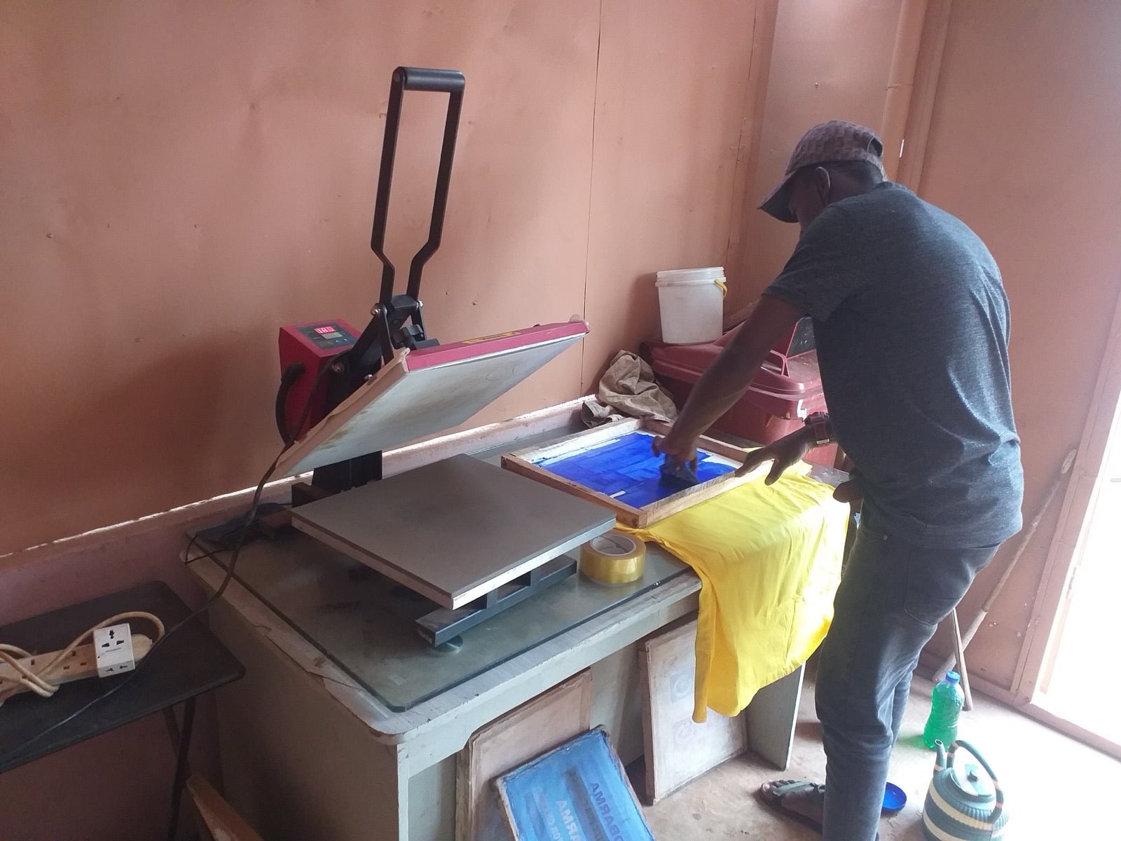 Graphic designer heat-pressing printed transfer film onto cotton tee shirt.