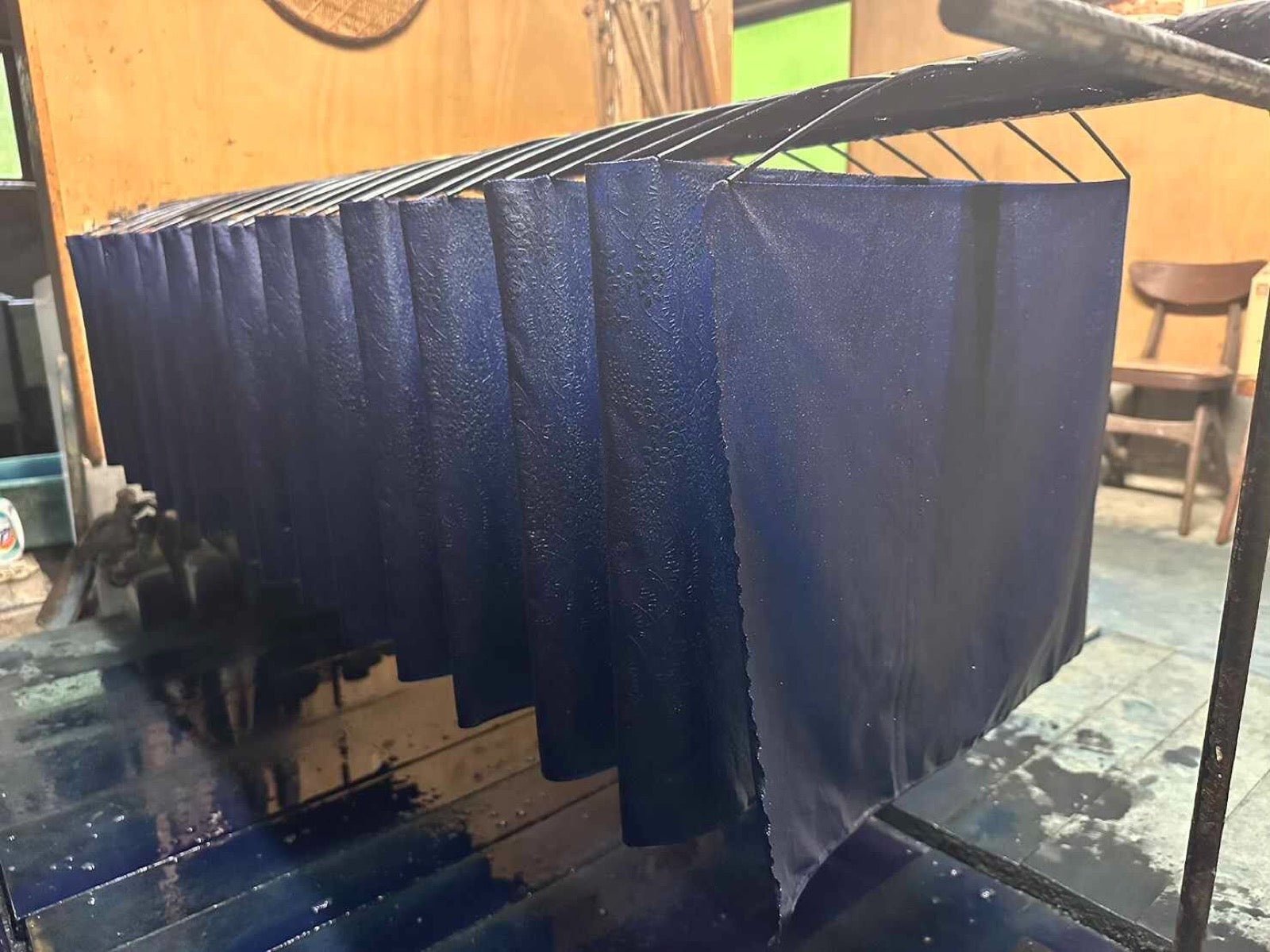 Indigo-dyed fabric lifted from fermentation vat showing oxidizing blue shade.