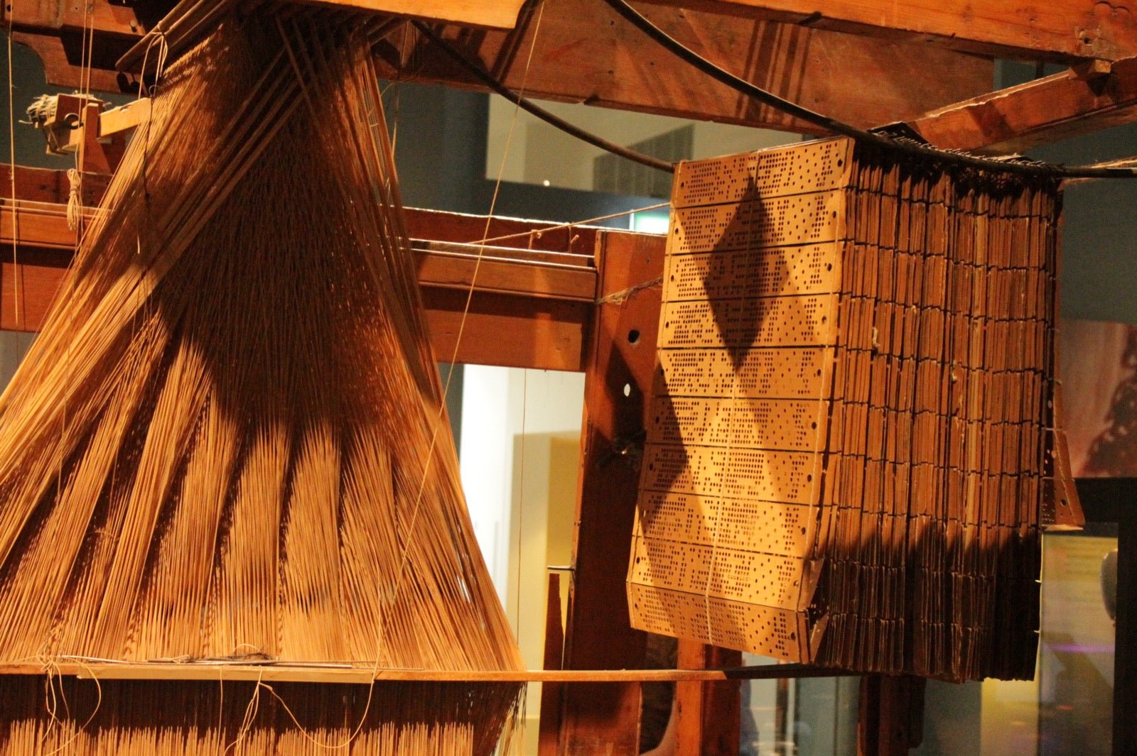 Historic jacquard loom with punch cards controlling individual warp threads.