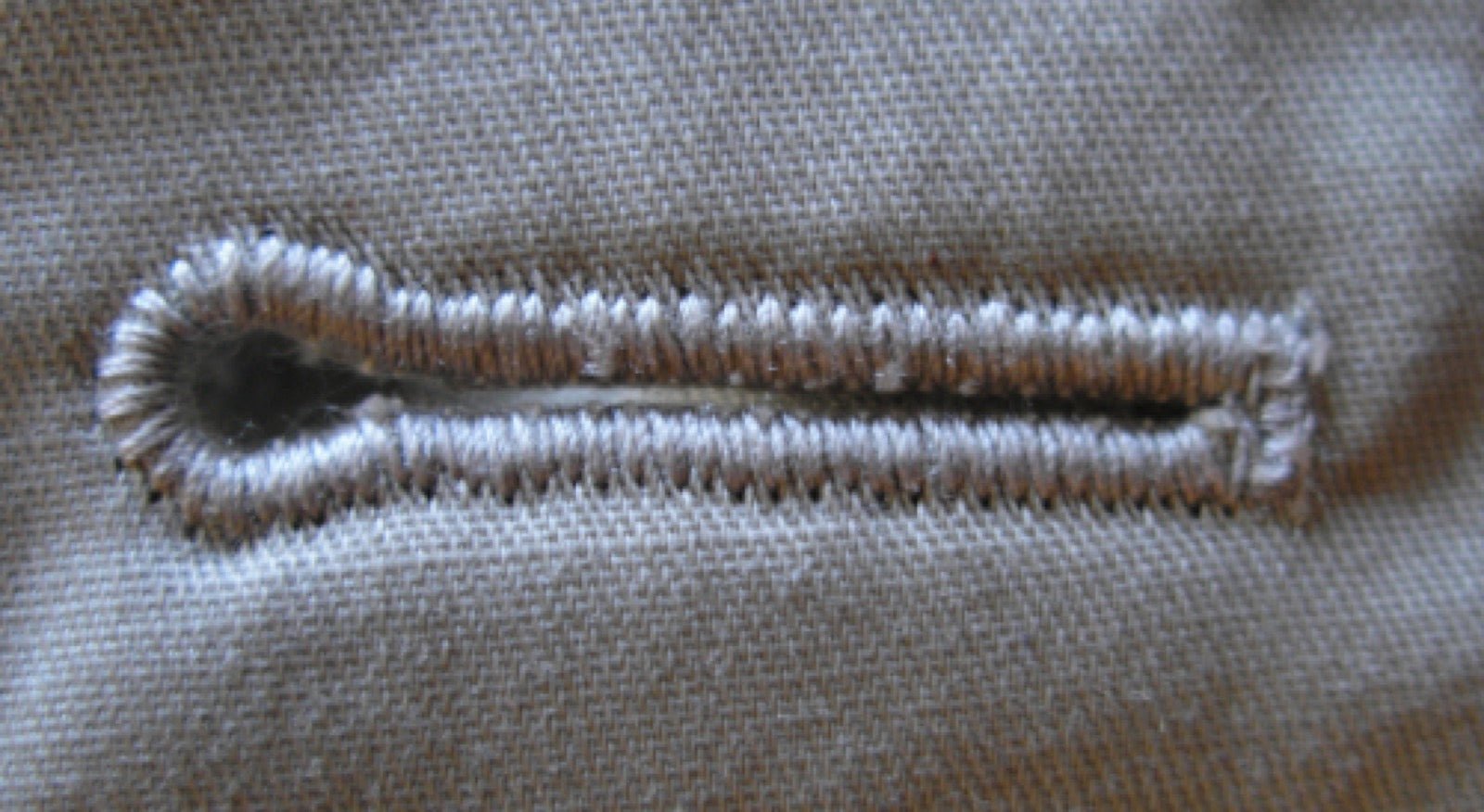 Keyhole buttonhole with round end on jacket lapel closure.
