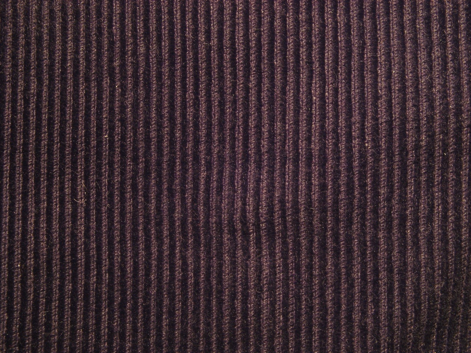 Needlecord trousers with very fine corduroy wales visible in close-up.