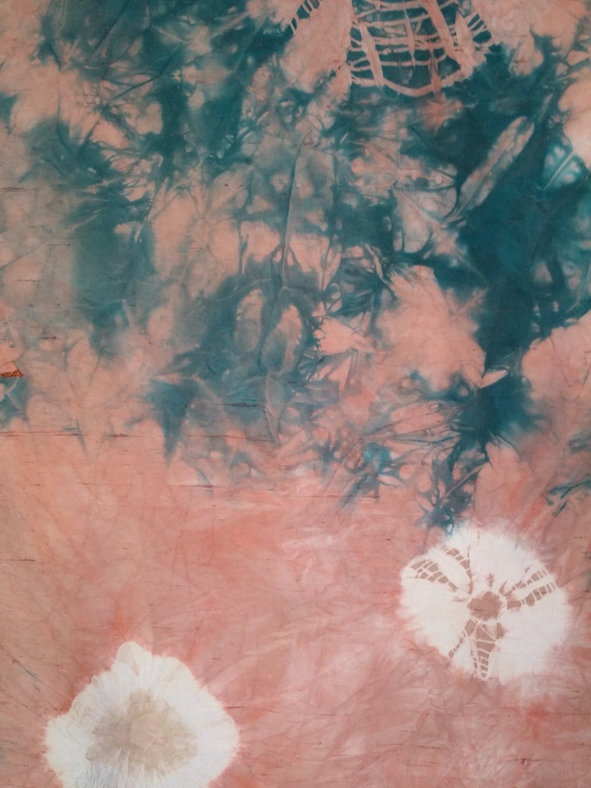 Tie-dye resist folds bound on silk scarf before immersion dyeing.