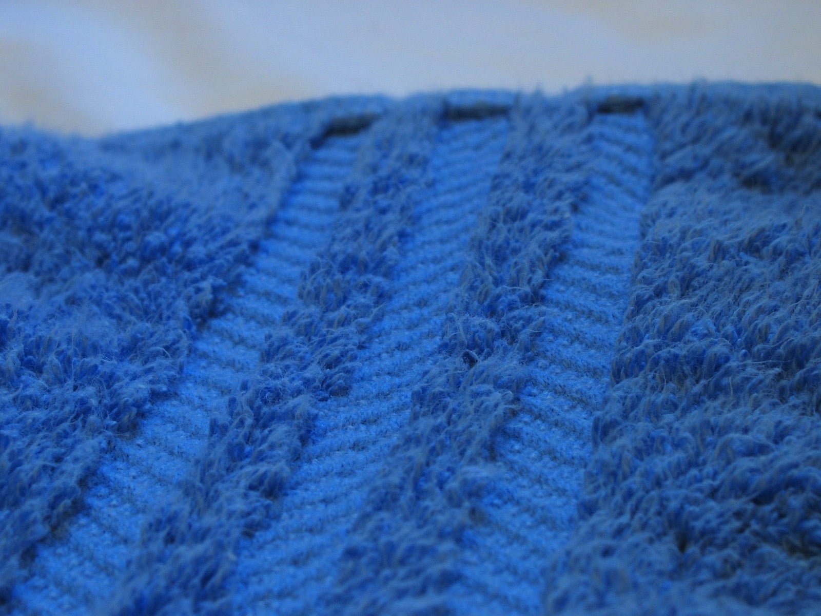 Close-up of blue terry towel showing uncut loop pile and decorative border.