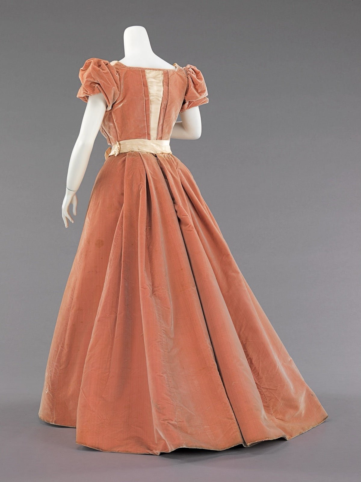 Evening dress with V-shaped back panel descending from shoulders.